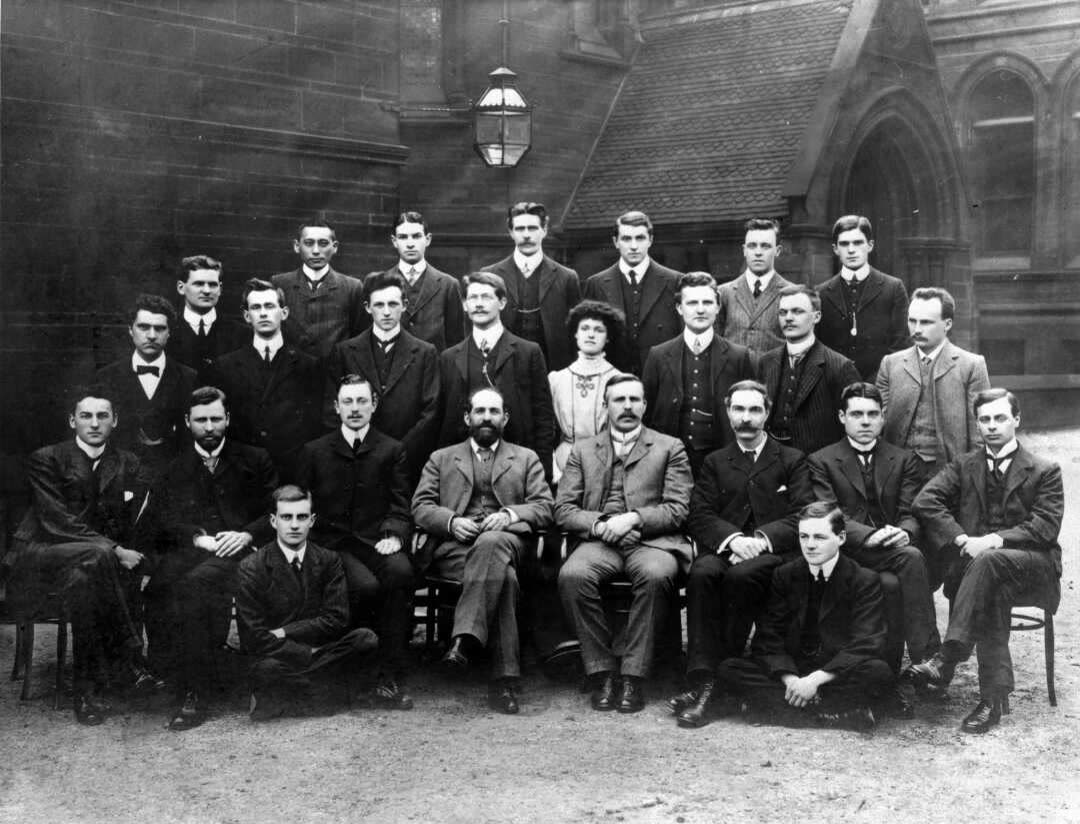 1910 年曼彻斯特大学物理实验室全体人员合影，三排人，前排中间坐着两位教授