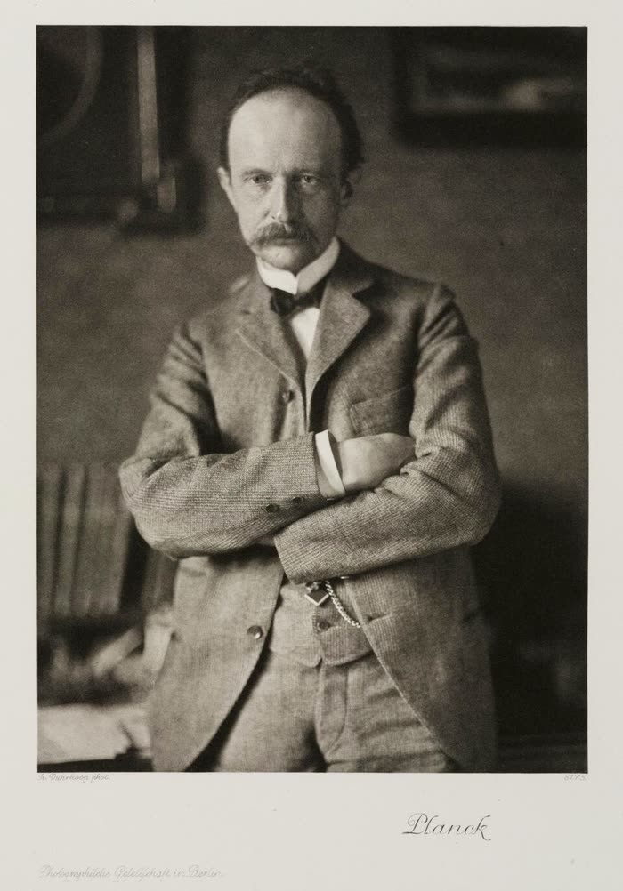 普朗克的黑白肖像，约 1910 年，双臂交叉站在书房里