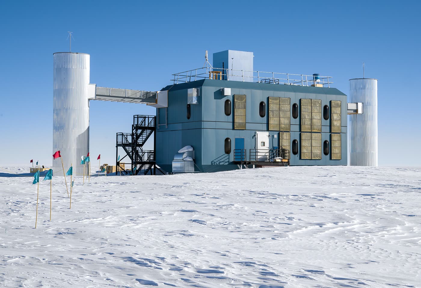 南极点雪原上的冰立方实验室，蓝色建筑两侧各有一座银色圆塔